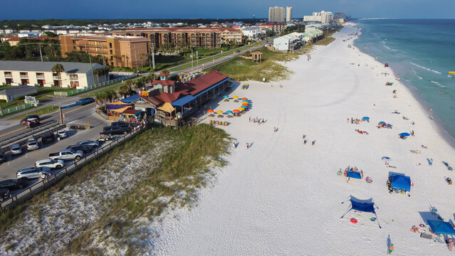 Sugar white sandy shoreline, colorful beach umbrella and people swimming, relaxing in Miramar Beach along 98 Scenic Gulf Drive, row of condominium, apartment, vacation rental