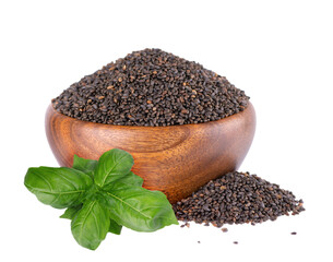 Basil seeds in wooden bowl, with green basil leaves, isolated on white background. Ocimum basilicum.