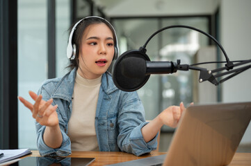 A professional Asian female radio host or podcaster is speaking into a microphone