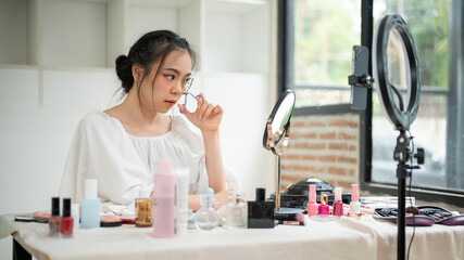 An attractive Asian female makeup artist curling the eyelashes
