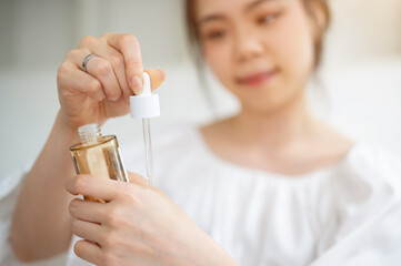 Close-up image of a beautiful Asian female beauty blogger trying a new facial serum on her hand