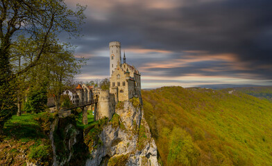 Lichtenstein Castle on mountain top in summer, Germany, Europe. This famous castle is landmark of Schwarzwald, Baden-Wurttemberg. Scenic view of fairytale Lichtenstein Castle and city in distance.