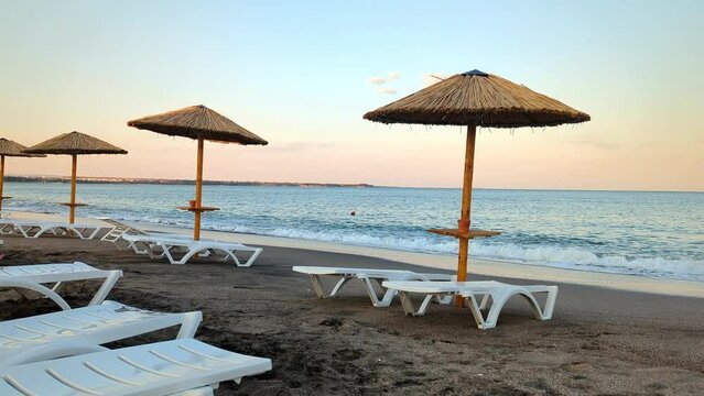 Sun loungers and umbrellas on the sandy shore of the Black Sea in the evening at sunset