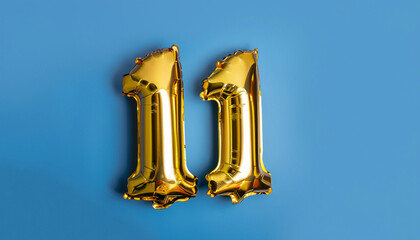 Banner with number 11 golden balloon with copy space. Eleven years anniversary celebration concept on a blue background.