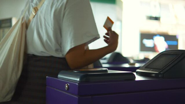 Passenger woman using contactless ticket for passing turnstile subway entrance gate at train station, high quality 4K big city transportation concept. Bangkok, Thailand.