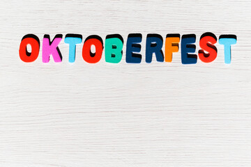 Fototapeta na wymiar colored letters with the word oktoberfest on a light colored wooden background and space for work
