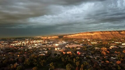 Aerial Panning Shot Of Houses Near Factory And Mountains At Sunset, Drone Flying Over City Against Cloudy Sky - Great Falls, Montana