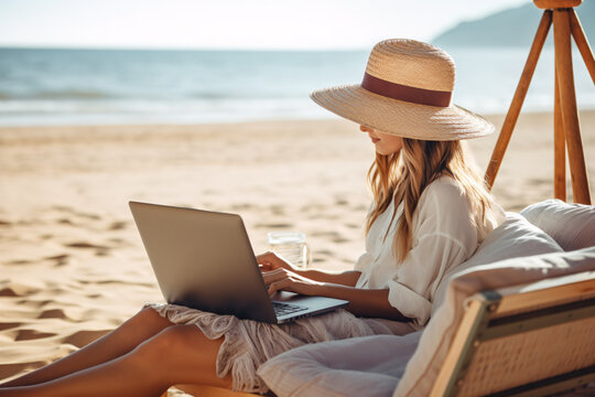 A woman working on a laptop while laying on the beach - Powered by Adobe