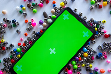 Smartphone with green screen and different colored beads with numbers and symbols