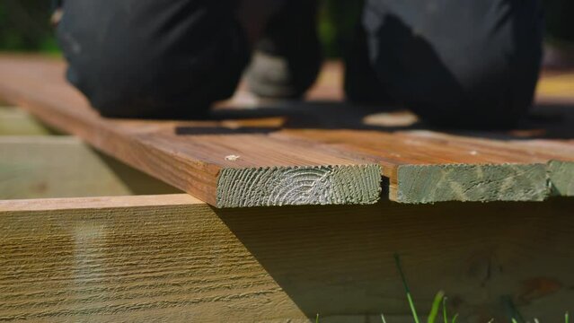 Deck construction, builder hand with electric screwdriver installing impregnated wooden boards