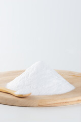 Bunch of white sugar on a wooden board on a light background, selective focus.