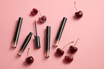 Minimalist concept for advertising lipstick products. Unbranded lipsticks with fresh cherries decorated on a pastel pink background. Cherry lip balm keeps lips soft and supple