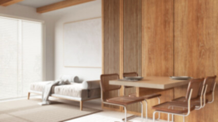 Blurred background, modern wooden dining and living room. Table with chairs, sofa, carpet and resin floor. Beams ceiling, japandi minimal interior design