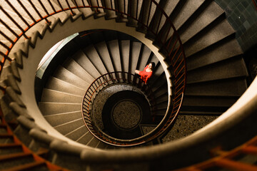 a girl in a red dress climbs a large spiral spiral staircase