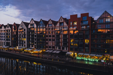Fototapeta premium Old town in Gdansk at summer dusk Poland. Sunset night view from the window rooftop on new modern architecture buildings Hotels to stay in Gdansk Place to eat over Motlawa river Wyspa Spichrzow Travel