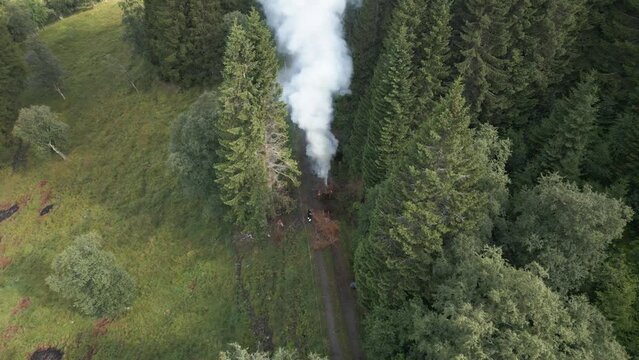 Farmers Feeding a Burning Waste Bonfire on a Path with Ashes Flying around Everywhere in Vik i Sogn, Norway. Still drone aerial footage.