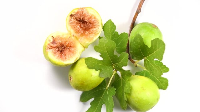 Fig fruits. Ripe sweet yellow, green figs fruit with leaves close up, rotating on white background, top view 