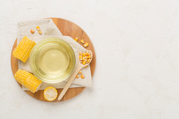 Corn oil with fresh cobs on concrete background, top view