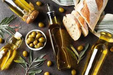 Fototapeten Bottles of olive oil, olives and slices of bread on gray background, top view © Atlas