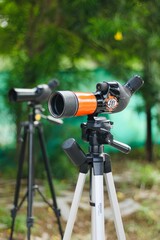Spotting scope mounted on tripod at an outdoor archery target range, featuring three boards