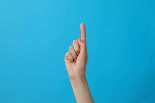 Female Hand Showing One Finger On Blue Background