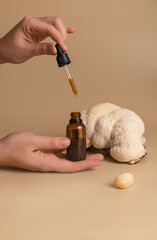 essential oil in bottle and cosmetic product in woman hand on studio beige background against...