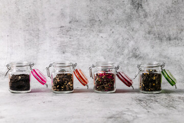 Assortment of glass jars filled with dry tea and copy space.