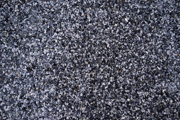 Small pebble stone background, dark wet gravel and gray dry gravel. Black small road