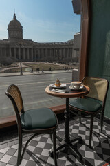 Cappuccino, delicious whipped creme dessert on wooden table in cafe with beautiful view on Kazan Cathedral in Saint Petersburg. Love and romance concept.