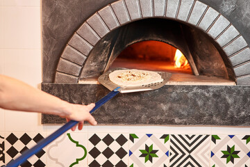 The chef prepares pizza. Raw pizza ready to bake. Cook in a apron in the kitchen. with a shovel in his hands. boxes for food delivery on background.