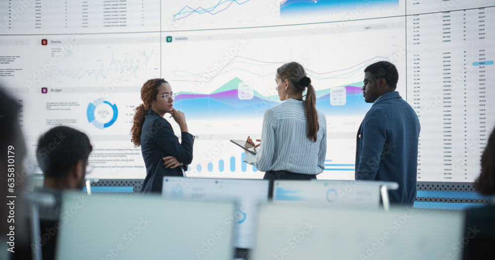 Poster Diverse Team Of Data Scientists Having A Meeting And Discussing Reports In a Modern Monitoring Office With Analytics Feed On a Big Digital Screen. Deep Learning Company With Employees Behind Computers