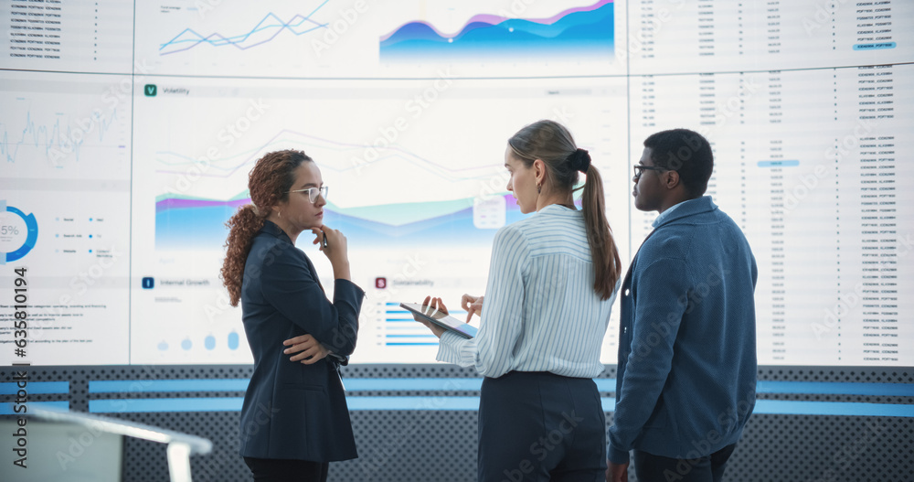 Poster Diverse Team Of Data Scientists Analyzing Information And Graphs On Big Led Wall In Modern Monitoring Office. Multiethnic Colleagues Discussing Financial Strategies, Risk Factors, Potential Deals.