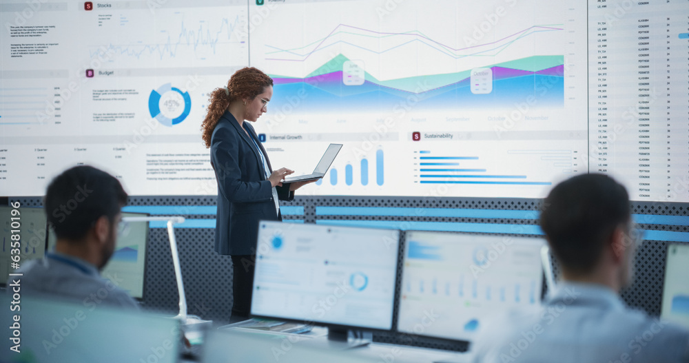 Poster Female Project Manager Using Laptop And Analyzing Information Graphs On Big Digital Screen In Monitoring Office. Hispanic Woman Working For Big Data Company, Diverse Employees Behind Desktop Computers