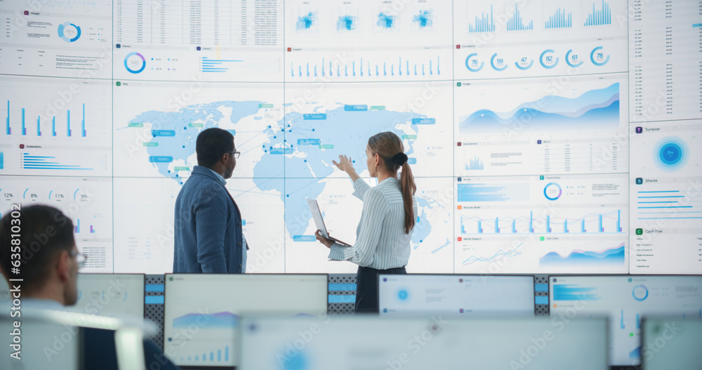 Aufkleber Back View Of Black Male Data Scientist Talking To Caucasian Female Supervisor In Front Of Digital Screen With World Map In Monitoring Office. Employees Working Behind Computers in Distribution Company