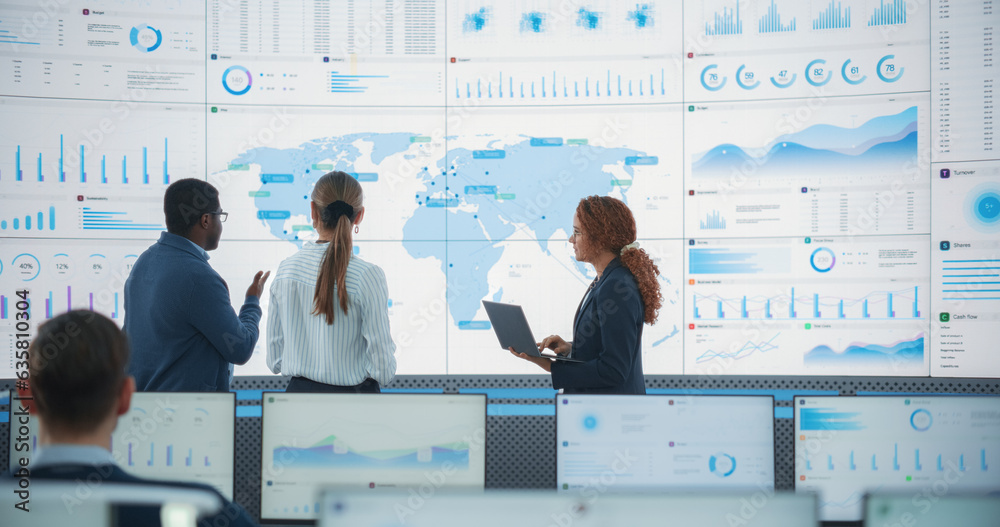 Aufkleber Diverse Team Of Specialists From Analytics Department Discussing Global Distribution In Front of Big Digital Screen With World Map In Monitoring Office. Multiethnic Employees Working Behind Computers.