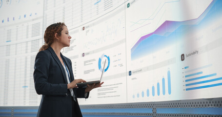 In the Monitoring Office: Successful Hispanic Businesswoman Holding Laptop Computer And Analyzing...