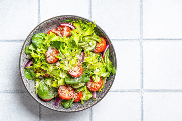 Green vegetable salad with fresh leaves. Top view on white tile background.