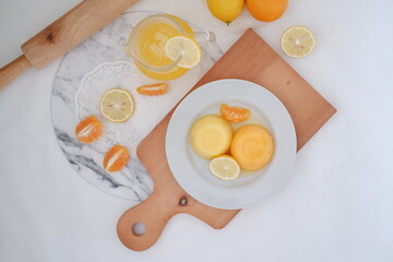 Orange jelly with fresh lemon and orange juice on a white background.