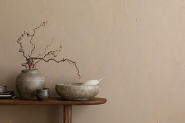 Minimalist composition of living room interior with copy space, wooden consola, ceramic bowl, gray vase with branch, cup, beige wall and personal accessories. Home decor. Template.