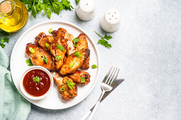 Chicken wings in bbq sauce on craft plate. Top view, close up on white stone table.