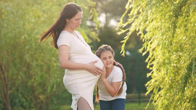 girl pregnant woman. daughter hugging her pregnant mother's belly. girl pregnant woman happy family kid dream concept. the girl loves her lifestyle unborn brother, mother equally loves two children
