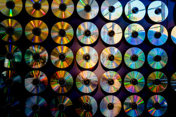 Des disques CD et DVD accrochés sur un mur avec un bel éclairage et de beaux reflets lumineux