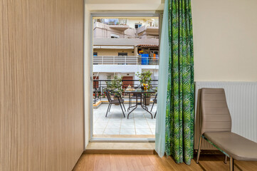 Inviting open door to balcony with garden chairs and table. Indoor-outdoor connection. Selective focus.