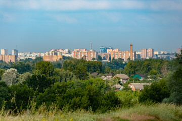 View of the Kharkiv on a summer sunny day. Cityscape with trees in the foreground and high-rise buildings on the horizon