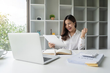 Fototapeta na wymiar Happy asian businesswoman raising hands with victory smiling happily with documents in hand. The concept of success at work