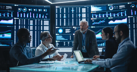 Team Of Data Scientists and Software Developers Discussing Reports in Monitoring Room with...