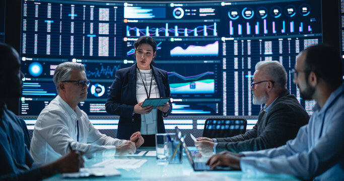 Multiethnic Chief Financial Officer Holding a Meeting with a Group of Fintech Investors. Diverse Team of Managers, Analysts and Board Members Having a Meeting in Front of Big Digital Screen