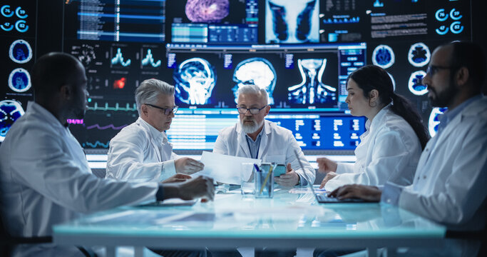 Global Pharmaceutical Research and Manufacturing Company Having a Meeting with a Group of Multiethnic Scientists, Doctors and Surgeons in a Room with Big Digital Screen with Patient Health Data