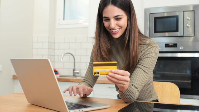 happy young attractive woman shopping online with a laptop computer using a credit card. e-commerce, business concept