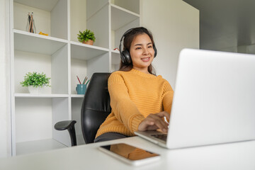 Fototapeta premium Asian woman using laptop at home and listening music on a headphones
